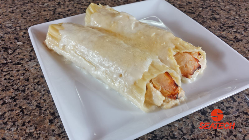 A photograph of Chilean crab meat cannelloni with crab meat in a bechamel sauce stuffed in mannicotti shells with melted mozzarella on top.