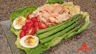A photograph of a crab louie salad with Chilean crab meat, asparaus, cherry tomatoes, deviled eggs and lettuce.