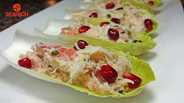 A photograph of crab salad on endive leaves with pomegranate. www.seatechcorp.com