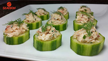 A portograph of English cucumber slices topped wtih crab salad and fresh dill.
