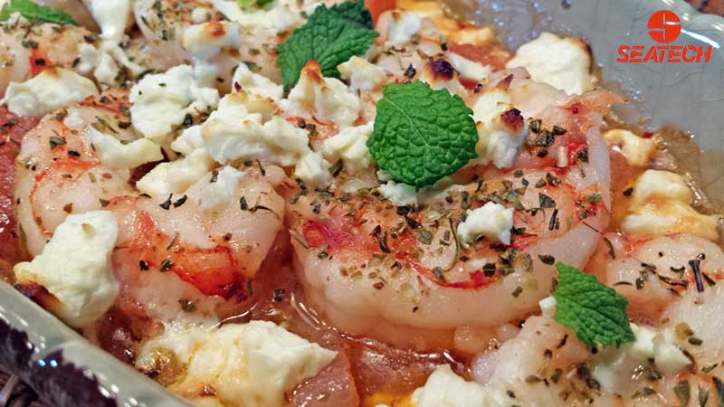 A photograph of Greek shrimp with roasted tomatoes, scallions, garlic and feta oven roasted and then topped with fresh mint.
