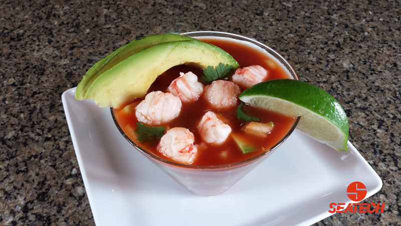 A photograph of a langostino lobster Mexican cocktail with langostino meat, avocado, cucumber, cilantro, onion, tomato juice and clam juice