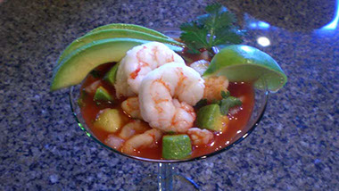 A photograph of a Mexican red shrimp cocktail featureing Argentine Red Shrimp, avocados, cucumbers, diced onions, tomato juice and clam juice.