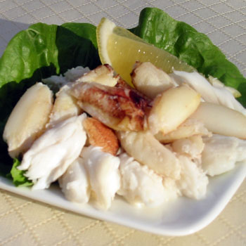 A photograph of pacific surf crab meat with a lemon wedge and lettuce.