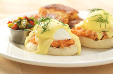 A photograph of salmon tartar eggs benedict wtih an avocado salsa and smashed red potatoes.