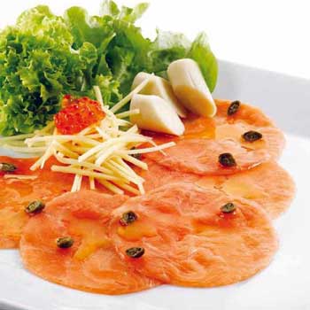 A photograph of salmon carpaccio with capers, motzarella cheese, salmon roe, olive oild and greens.