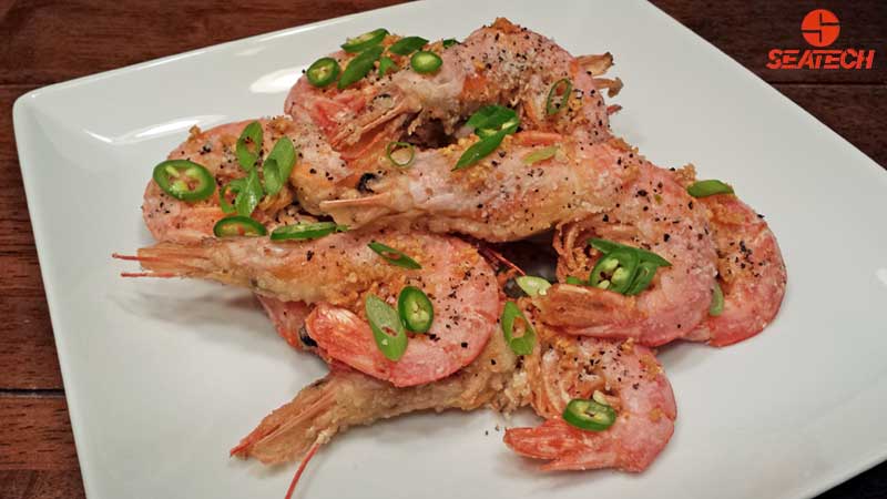 A photopraphe of salt and pepper argentine red shirmp with scallions, fried garlic and sliced sarrano peppers.