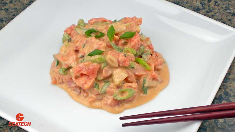 A photograph of spicy salmon tartar poke with salmon tartar, green onions and soy sauce mixed with mayonnaise and sriracha sauce.