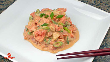 A photograph of spicy salmon tartar poke with salmon tartar, green onions and soy sauce mixed with mayonnaise and sriracha sauce.