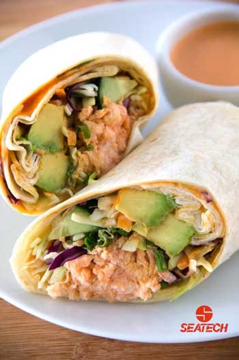 A photograph of a sriracha crunch salmon wrap with dipping sauce.